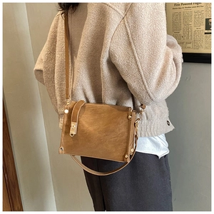 Close-up of brown vintage leather crossbody bag featuring a golden turn-lock closure