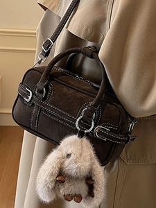Sac Boston marron avec surpiqûres blanches et charme de lapin en peluche porté par mannequin