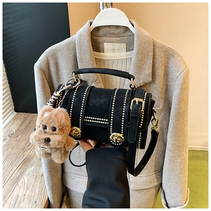 Detail der schwarzen Boston-Bag mit Nieten, Drehverschluss und braunem Plüsch-Anhänger