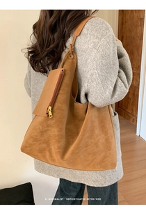 Detail of a large brown suede tote bag featuring a practical small zipper pouch attachment