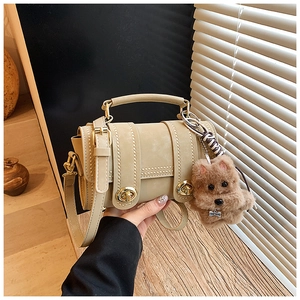 Detail der beigen Boston Tasche mit Goldbeschlägen, Ziernähten und Hund-Anhänger