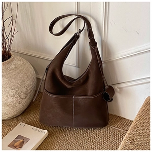 Detailed close-up of a large brown hobo bag featuring contrast white stitching and side pockets