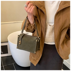 Detailed view of vintage dark green crossbody bag with gold rivets and leather texture