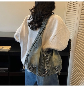 Detailed back view of a large washed denim tote bag with metallic stud accents on a model