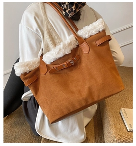 Detail of a large brown suede tote bag with white plush trim and leather buckle strap