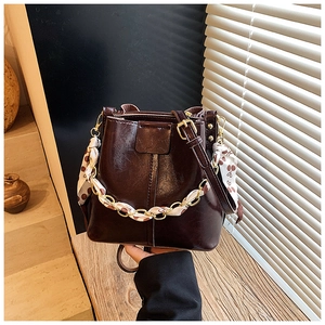 Detail of deep brown bucket bag with gold chain and floral scarf wrap accessory
