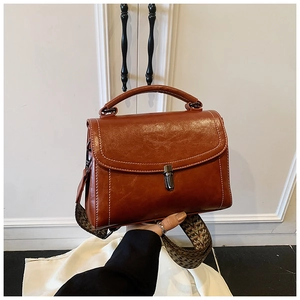 Detail of vintage brown shoulder bag with oiled leather texture and jacquard strap