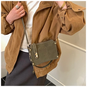 Detail of vintage olive green messenger bag with gold metal buckle shown on model