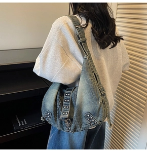 Detail view of a large washed denim tote bag with silver studs and adjustable strap