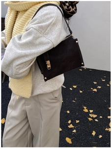 Detail of vintage coffee brown suede crossbody bag with gold lock and metal rivets