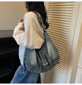 Detailed macro view of heavy washed denim tote with retro metal rivets on large hobo bag
