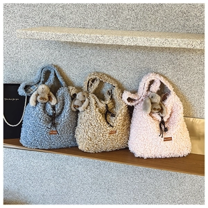 Close-up of fuzzy lamb wool tote bags in blue, beige, and pink with cute bunny charms
