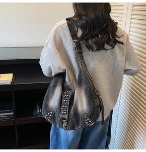 Black washed denim punk crossbody bag with silver rivets shown on a model