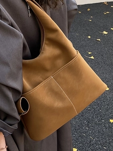 Brown vintage leather tote bag with contrast stitching in an autumn outdoor setting