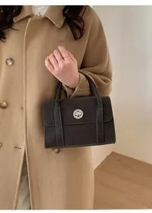 Detail of a black structured handbag featuring a silver round clasp and dual decorative straps