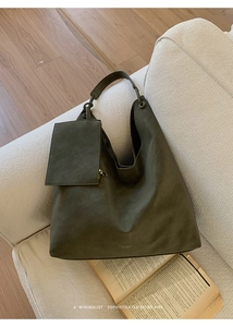 Detail of olive green suede hobo bag with matching mini pouch on a cozy sofa