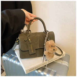 Detail of dark olive green square handbag with cute bear charm and fashion tag