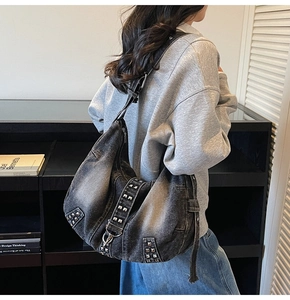 Detail of black washed denim tote bag featuring silver studs and adjustable shoulder strap