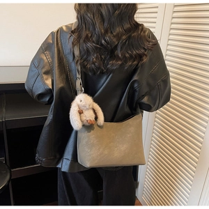 Detailed view of gray-green hobo bag featuring a cute bunny plush charm on a shoulder strap
