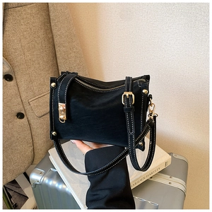 Close-up of black leather crossbody bag with white stitching and gold metal hardware detail