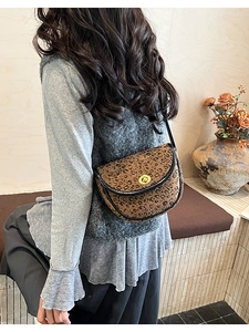 Détail du sac selle à motif léopard avec boucle dorée porté par un mannequin femme