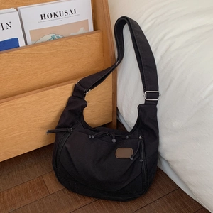 Detail of black canvas tote bag showing metal buckle on wide adjustable shoulder strap