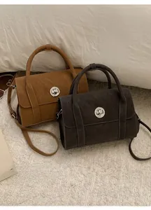 Detail view of vintage suede crossbody bags with circular metal buckles in caramel and grey