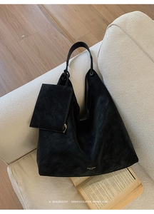 Detail of black suede hobo bag texture with a matching zipper pouch on a sofa