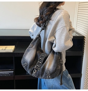 Detail of washed denim tote bag with silver square studs shown on model shoulder