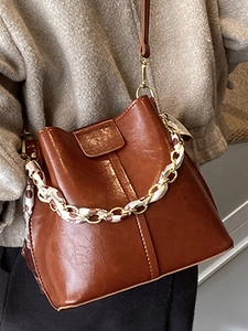 Brown vintage bucket bag with scarf-wrapped chain handle and crossbody strap