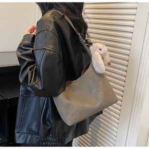 Close-up of a minimalist gray hobo bag with a soft plush rabbit charm detail