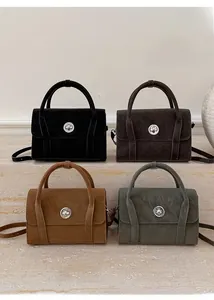 Detail view of suede textured handbags featuring a circular metal twist lock and top handles