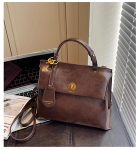 Detailed close-up of dark brown vintage backpack with gold circular swivel lock and oil wax texture
