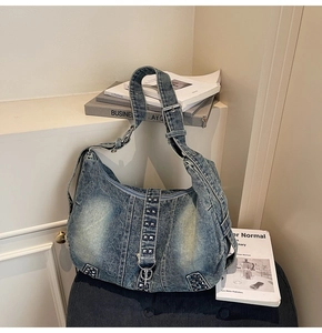 Detail of blue washed denim tote bag with silver square rivets and adjustable strap
