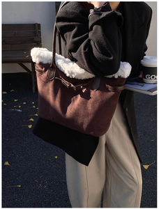 Close-up of brown suede tote bag featuring white faux fur trim and leather handles