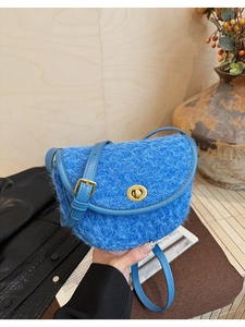 Détail du sac selle en peluche bleue avec fermoir en métal doré et bandoulière en cuir