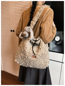 Detail of beige fleece tote bag featuring a plush rabbit charm and star-picking leather tag