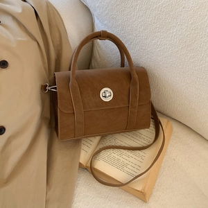 Detailed shot of brown vintage handbag with silver round twist lock and fine grain texture