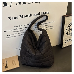 Close-up of black quilted tote bag showing high-gloss texture and luxury stitching