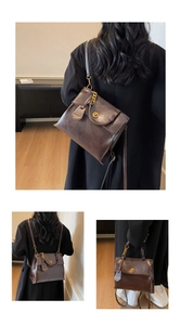 Detail view of retro brown leather backpack with gold metal turn lock and chain strap