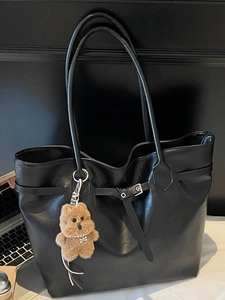 Large black minimalist tote bag with silver buckle detail and plush bear charm for commuting
