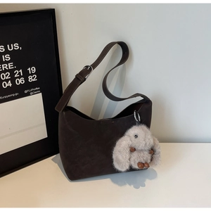 Detail of vintage brown suede shoulder bag with cute rabbit charm on white surface