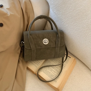 Detail view of vintage olive green leather handbag with silver clasp on fabric background