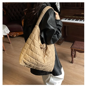Detail of khaki quilted tote bag featuring a diamond pattern and glossy nylon texture