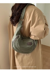 Model wearing a large army green canvas tote bag with a retro crescent shape and leather patch