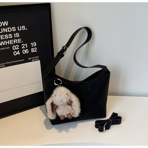 Close-up of black matte shoulder bag with a cute plush rabbit charm and extra strap