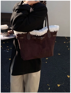 Detail view of large dark brown suede tote bag with white faux fur trim on a female shoulder