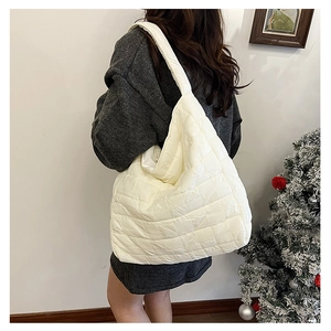 Detail view of large beige quilted tote bag shown on model in cozy home setting