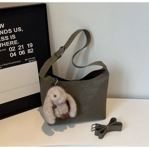 Detail of vintage square underarm bag with plush rabbit charm and adjustable strap