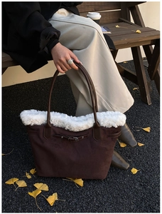 Detail of a large brown suede tote bag with white faux fur trim and belt buckle accent